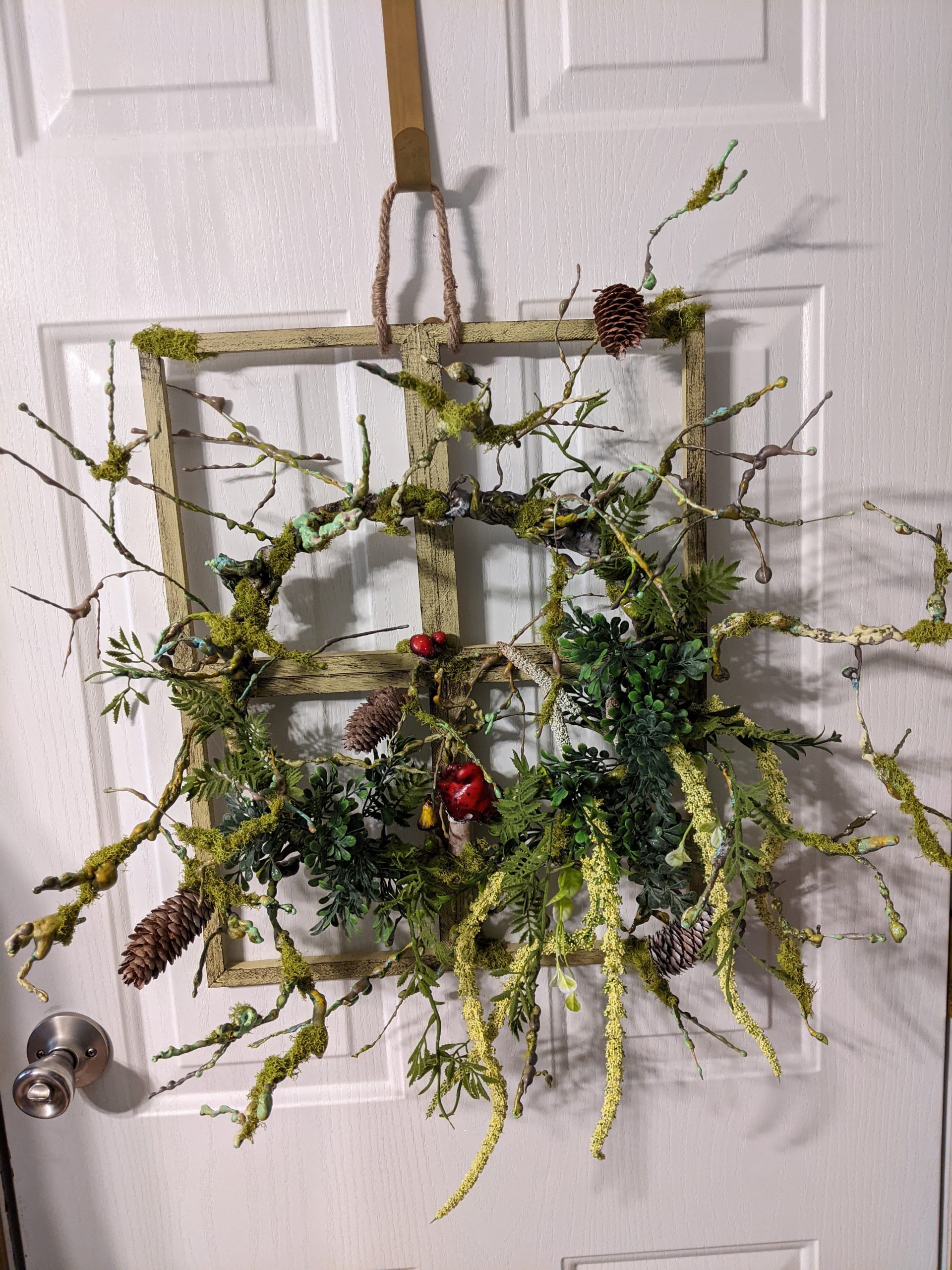 Window pain wreath with natural and hand sculpted elements.